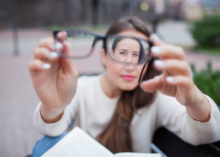 Woman holding a pair of glasses in front of her eyes